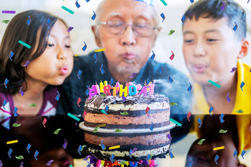 Happy grandfather and grandchildren blowing candles