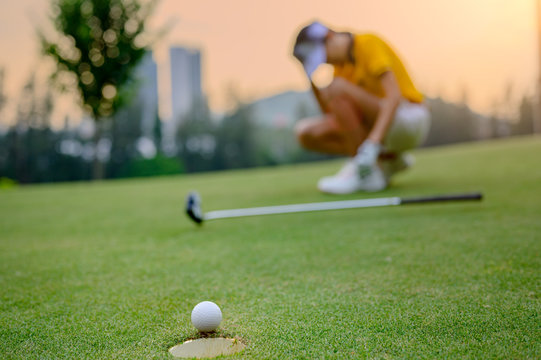 golf ball unsuccessfully dropped into golf hole, putted by young woman golf player is acting an upset disaster or disturb or disappointed in background