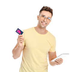 Young man with credit card and tablet computer on white background