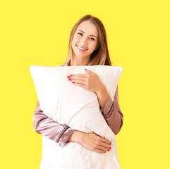 Beautiful young woman with pillow on color background