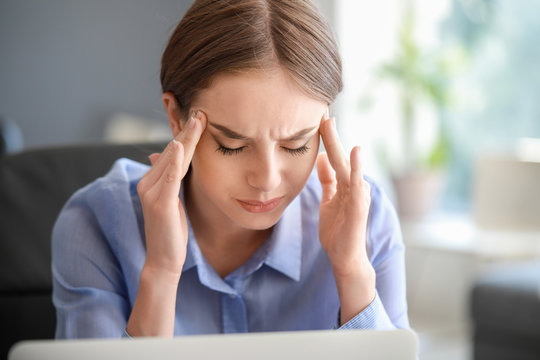 Young Woman Suffering From Headache In Office