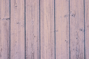 The texture of the old wall of the house of wooden boards painted with pink paint. Peeling paint flakes