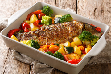 Tasty baked fish carp with summer vegetables close-up in a baking dish. horizontal