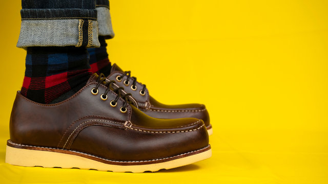 Men fashion with brown shoes leather and jeans on yellow background.