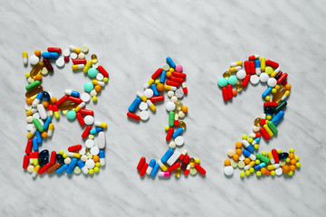 Text B12 made of different pills on light background