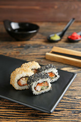 Plate with tasty sushi rolls on table