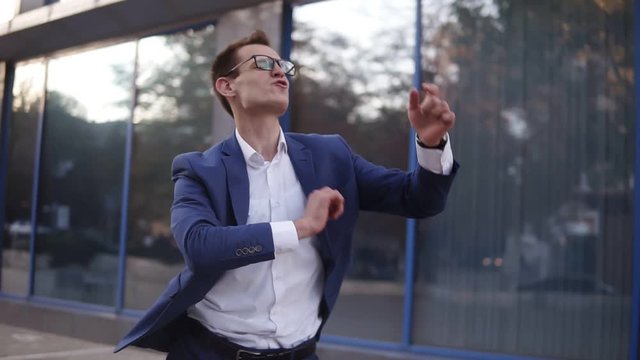 Successful businessman dancing crazy happy funky dancing. Caucasian street dancer freestyle in the city, celebrating his project victory. Slow motion
