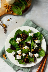 Vitamin snack. Salad with spinach, feta cheese, beetroot and walnut, vegetable oil sauceon a concrete table. Top view flat lay background.