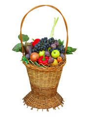 Wicker basket filled with colorful organic vegetables fresh harvest plums, grapes and apples isolated
