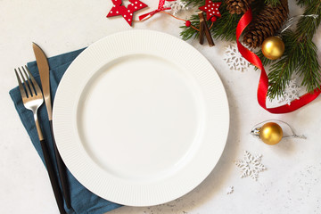 New Year, Christmas dinner, table setting. Christmas table with plate, silver and Fir branch on a white concrete table. Top view flat lay background. Copy space.