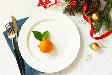 New Year, Christmas dinner, table setting. Christmas table with plate, silver and Fir branch on a white concrete table. Top view flat lay background.