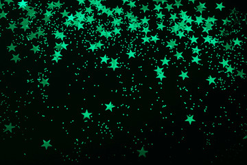 biscay green star confetti and glitter on a black background - Christmas / New Year party festive...