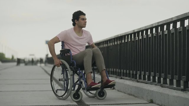 Sad disabled on wheelchair look to the river and leave away