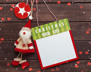 Christmas wish list with toy Santa Claus on wooden background