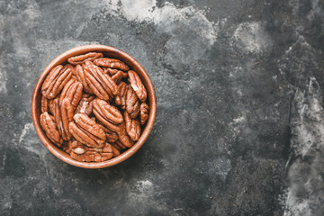 Obraz na płótnie Canvas Bowl with tasty pecan nuts on dark background
