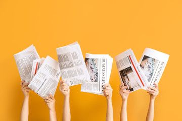 Female hands with newspapers on color background