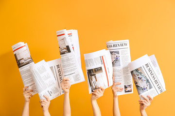 Female hands with newspapers on color background - obrazy, fototapety, plakaty