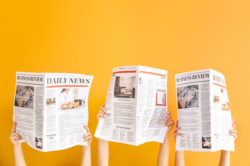 Female hands with newspapers on color background