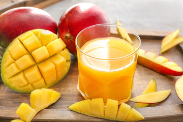 Tasty mango and glass of juice on table