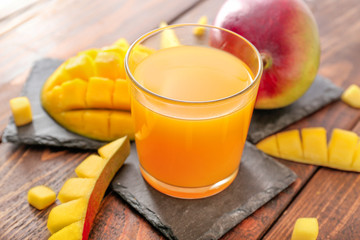 Glass of tasty mango juice on table
