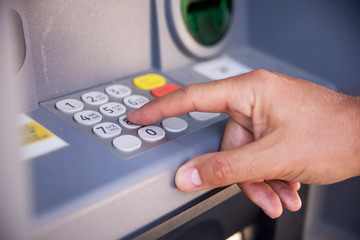 Close-up of hand entering PIN/pass code on ATM/bank machine keypad