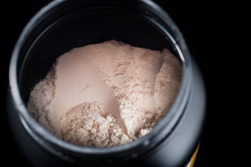 Black plastic jar with a sports supplement protein. On a black background.