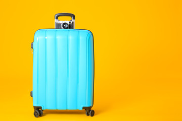 Packed suitcase and photo camera on color background. Travel concept