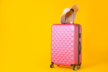 Packed suitcase and hat on color background. Travel concept