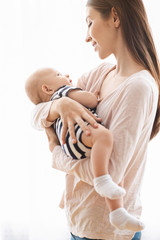 Young happy woman tenderly holding her newborn baby in arms