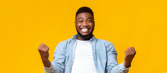 Happy african american man rejoicing success with clenched fists