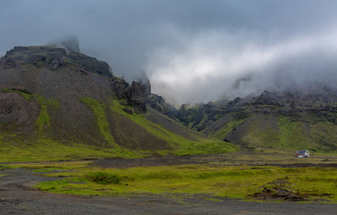 Mountain valley topped by clouds. Lonely house at the foot of the mountains