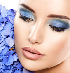 Closeup face of young beautiful woman with a blue makeup of eyes.