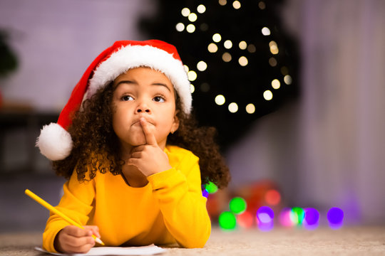 Pensive little black girl thinking what to ask from Santa Claus