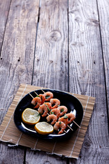 Boiled shrimp in a black plate on gray boards.