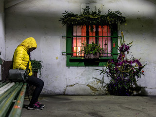 A homeless woman sits on a bench at Christmas holidays. A passenger waits for a night transport in...