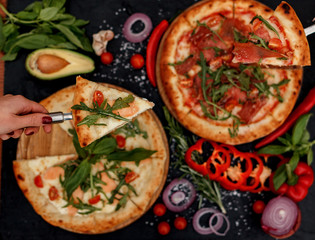 Pizza and ingredients on a black background. Italian food, vegetarian vegetables, avocado.