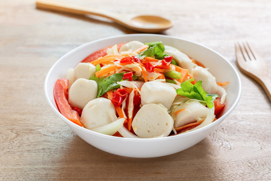 close up of spicy fish ball salad in a bowl on wooden table. delicious thai style food menu.