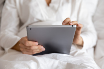Close up view of woman using tablet computer in bed
