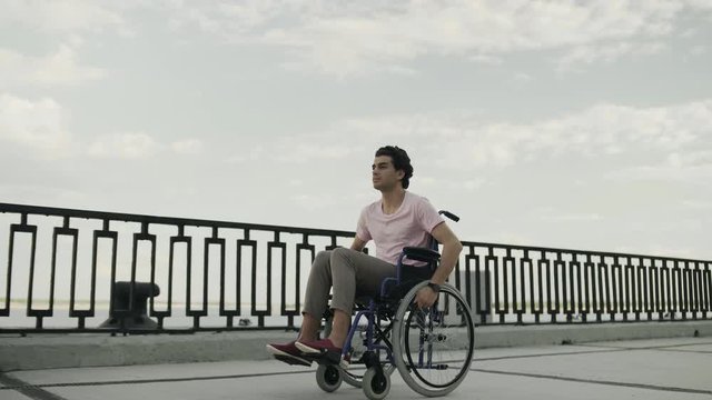 The unhappy man ride a wheelchair along the promenade