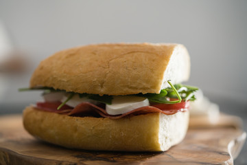 ciabatta sandwich with salami and mozzarella cheese on olive board