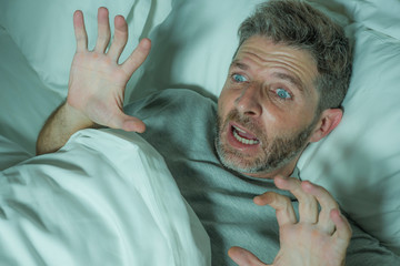  stressed and scared man alone in bed awake at night in fear after having a nightmare feeling...