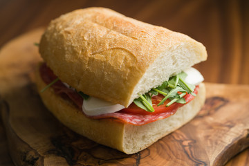 ciabatta sandwich with salami and mozzarella cheese on walnut table