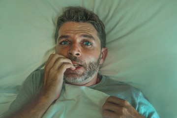  stressed and scared man alone in bed awake at night in fear after having a nightmare feeling...