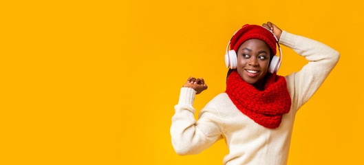 Excited afro girl with wireless headset listening to music, dancing