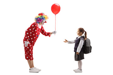 Obraz na płótnie Canvas Clown giving a red balloon to a schoolgirl