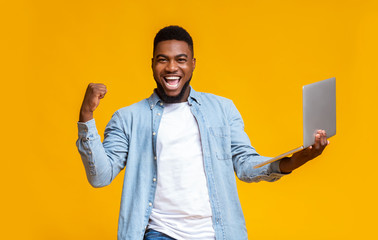 Happy black guy rejoicing success with laptop