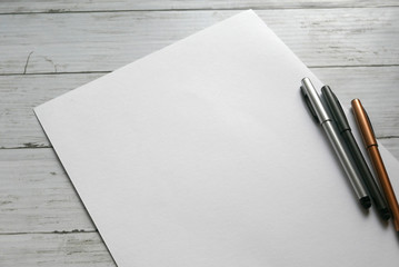three pen on white paper background lay on white wooden background. Copy paste for text, logo and...