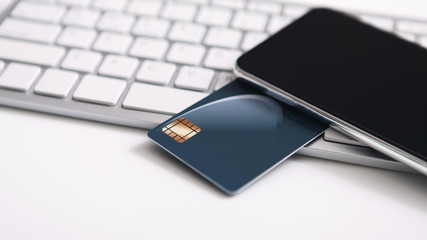 Credit card with chip and blank smartphone on computer keyboard