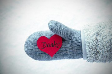 Red Heart With German Calligraphy Danke Means Thank You. Human Hand In A Glove With Fleece And Snow.