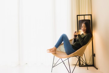 Fototapeta premium Portrait beautiful young asian woman hold coffee cup and sitting on sofa chair